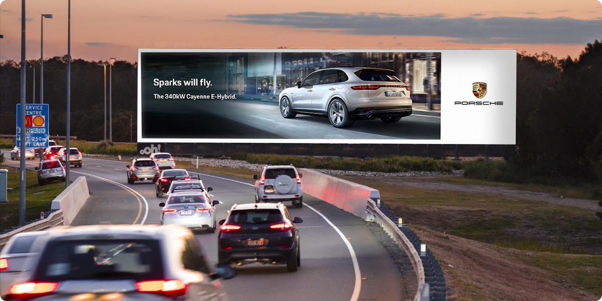 Porsche billboard on the side of a highway with cars speeding past